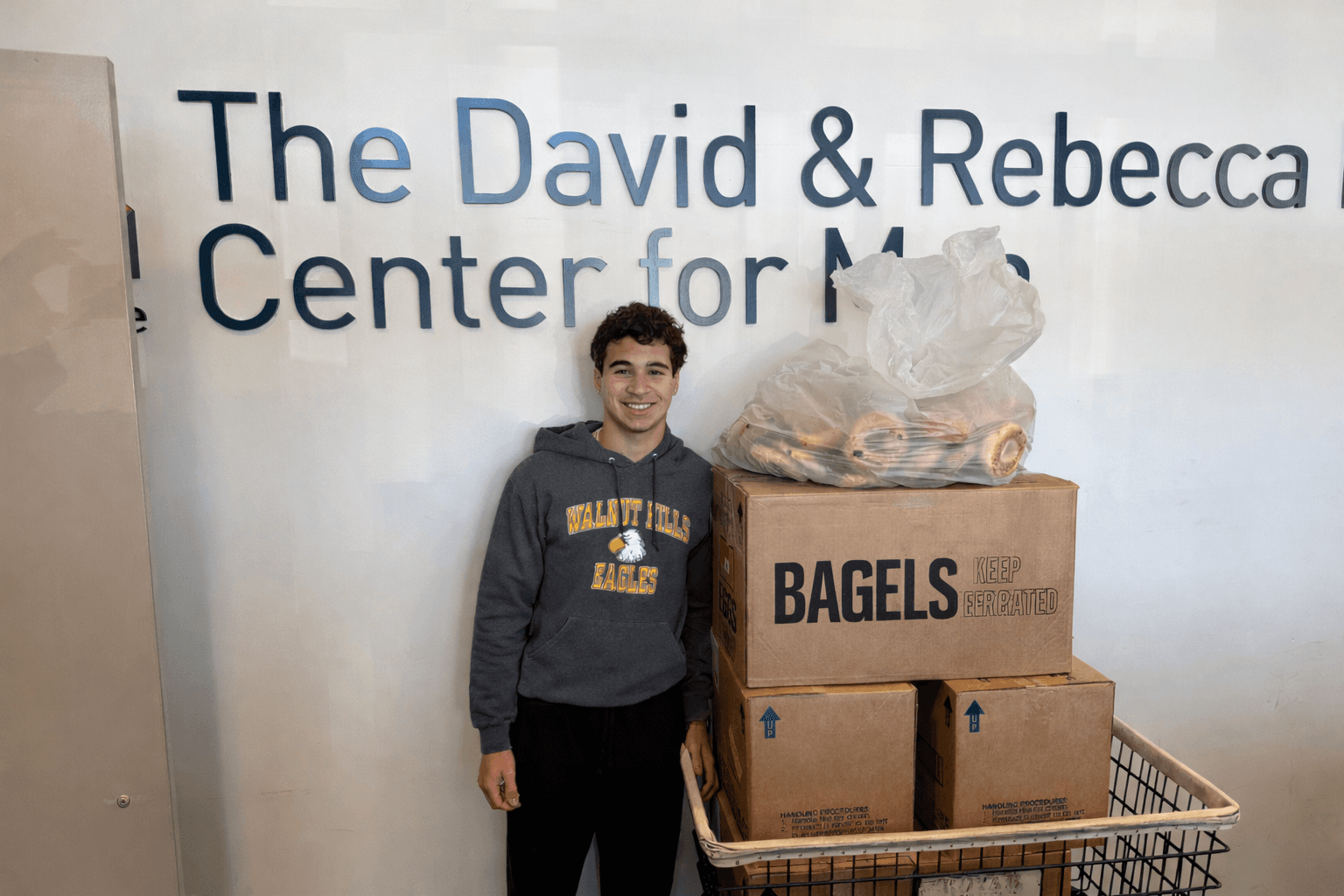 KneadLA volunteer with a cart of donated bagels and bread at a community center